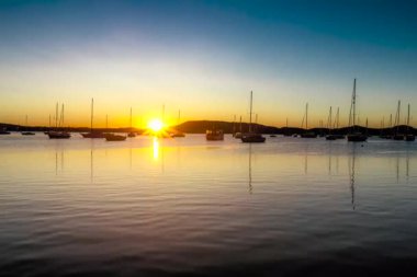A beautiful time lapse of sunset with a lot of boats in the sea at the coast