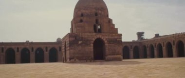 A young female entering the frame against the Mosque of Ibn Tulun in Cairo, Egypt