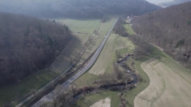 ドイツのバイエルン州で晴れた日に森に覆われた丘の近くの交通の鳥の目のビュー — ストック動画
