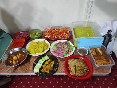 A high-angle shot of different types of tasty food in plastic containers and plates for a celebration