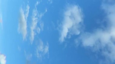 A vertical shot of moving white clouds in a blue sky