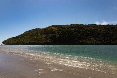 Yeşil bir tepenin güzel manzarası. Parlak su kenarında. Mavi güneşli gökyüzü.