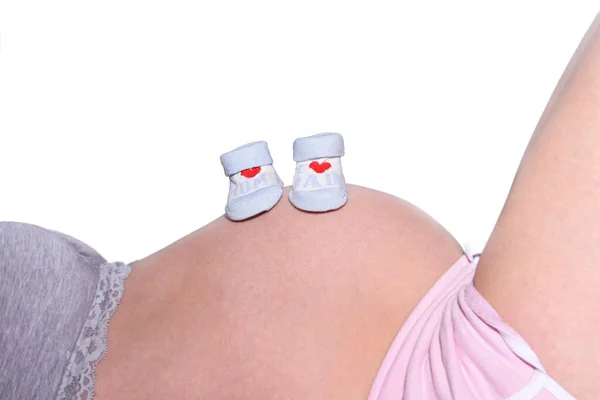妊婦の胃の上に赤ちゃんの靴のペアのクローズアップショット — ストック写真