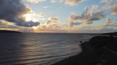 Bulutlu bir günbatımı gökyüzünün altında deniz manzarası