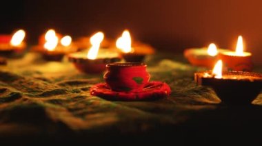 Diwali Diya oil lamps are placed on a table among other glowing Diya lamps. Decorative Diya lamps.