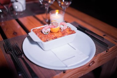 Masadaki parlak tencerede deniz ürünleri lazanyası.