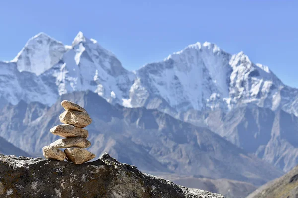 A stack of rocks with a mountain range in the background - a cairn
