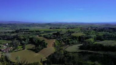 Drone flight over a typical Tuscan landscape with green hills, cypress, vineyards and the agricultural farms with buildings made of natural stone