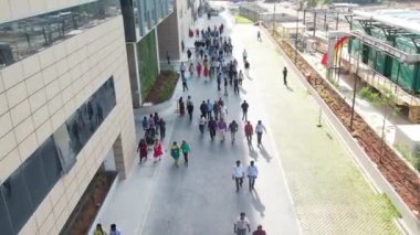 An aerial slow movement around people walking near glass building in IT park of Chennai