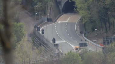 İtalya 'nın Como şehrinde ağaçlarla çevrili bir otoyol üzerindeki trafik arabalarının ve kamyonların hava görüntüsü.