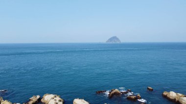 An aerial view of calm clear water and rocky seacoast
