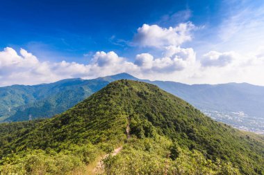 Dağ sıralarının güzel manzarası ve altında bulutlu gökyüzü olan bir kasaba.