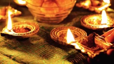 Diwali Diya oil lamps are placed on a table among other glowing Diya lamps. Decorative Diya lamps.