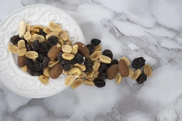 A Top view of a trail mix in a white plate on a marble table