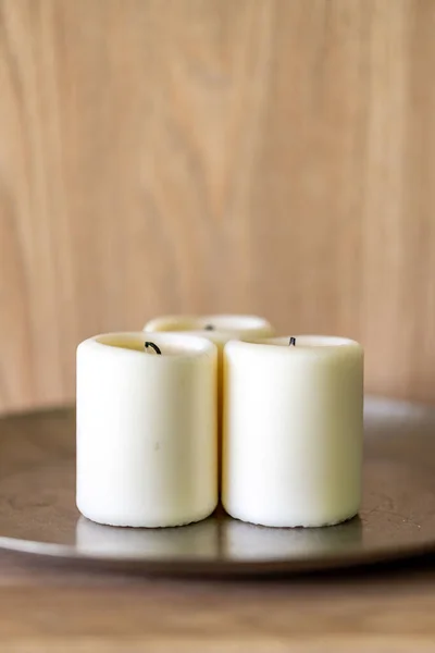 木製のテーブルの上に3本の白いろうそくの垂直ショット — ストック写真