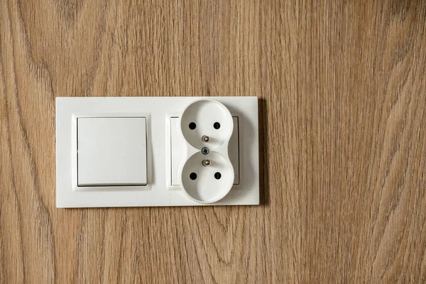 插头一种白色电源插座 两根插头插在有木制表面的墙上 — 图库照片