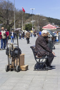İstanbul, Türkiye 'de çalışan ve telefonla konuşan yaşlı bir adamın bankta oturduğu dikey bir çekim