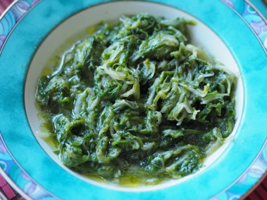 Erimiş tereyağı ile kaplanmış lezzetli bir ıspanak yemeğine yakın plan.