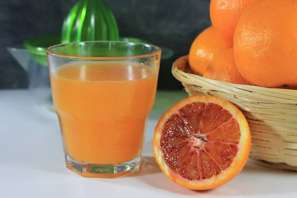 Glas Mit Orangensaft Auf Weißem Tisch Mit Korb Voller Orangen — Stockfoto