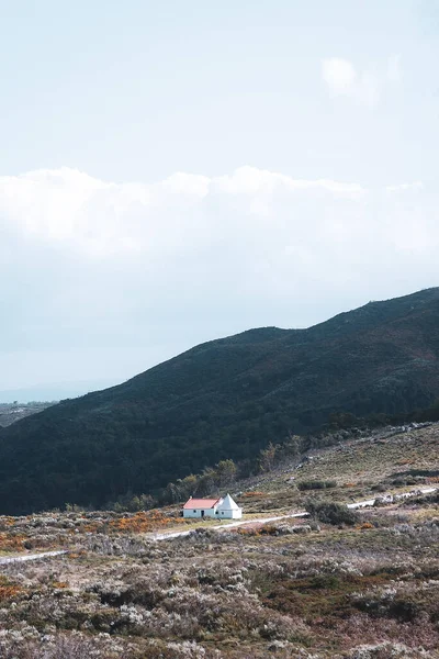 一个垂直拍摄的山地和中间的一座小小的白色建筑 — 图库照片