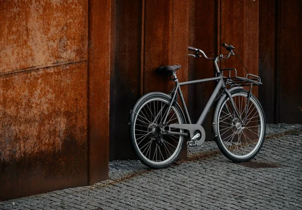 一辆自行车停在室外纹理地面上的木制墙壁上 — 图库照片