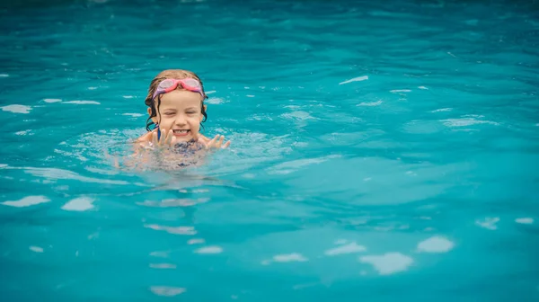 A small girl swimming in the pool in a daylight