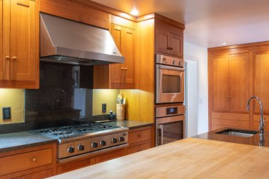 Fırını, lavabosu, musluğu ve ahşap dolabı olan modern bir mutfak.