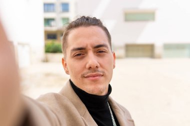 Genç bir melez adamın portresi. Şehirde akıllı bir telefonla selfie çekiyor. Uzayı kopyalıyor.