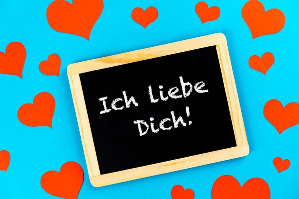 ドイツ語で君を愛してる赤いハートの青い背景の黒板に書かれた言葉 — ストック写真