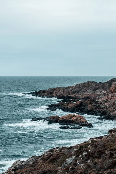 靠近泡沫般的海浪的棕色悬崖峭壁的垂直拍 — 图库照片