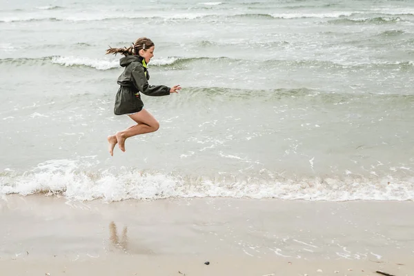 A closeup shot of a Polish girl jumping near the sea