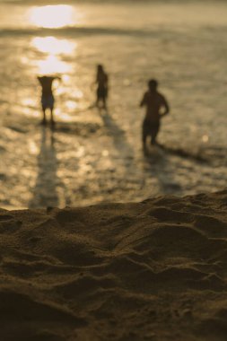 Sahilde gün batımında bir grup arkadaşın dikey çekimi.