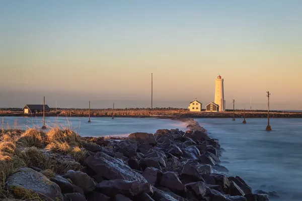 夕日の間にアイスランドの洞窟島と灯台の海岸の景色 — ストック写真