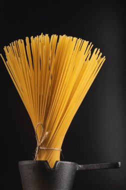 Makarna, koyu arkaplanda küçük bir tencerede pişirilmeye hazır.