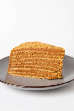 Beyaz arka planda izole edilmiş bir bal pastasının dikey görüntüsü.