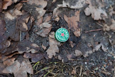 Heineken 'in orjinal şişe kapağının ormandaki çevre kirliliği kavramının üst görüntüsü.