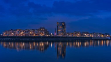 Su yüzeyinde yansıması olan gece şehri manzarası..