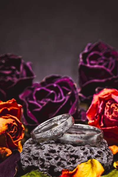Renkli Güllerle Çevrili Gümüş Alyansların Dikey Yakın Çekimi — Stok fotoğraf