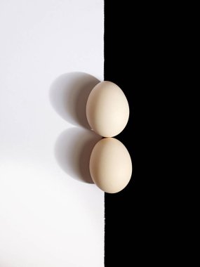 Siyah ve beyaz bir yüzeyde iki yumurtanın üst görüntüsü.