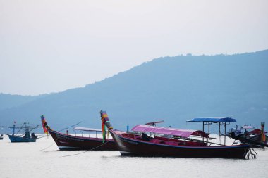 Sudaki kayıklar tepenin ve gökyüzünün arka planına karşı.