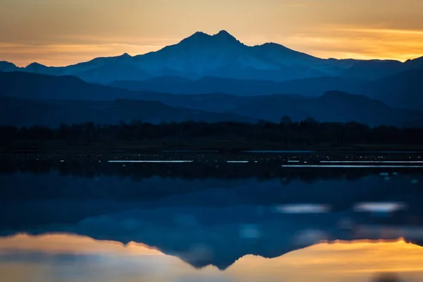 A beautiful shot of mountains reflected on the surface of a lake during the sunset