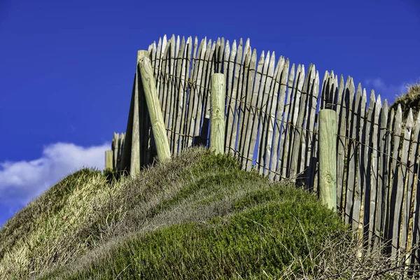 A closeup of wooden fence on hill against a cloudy blue sky