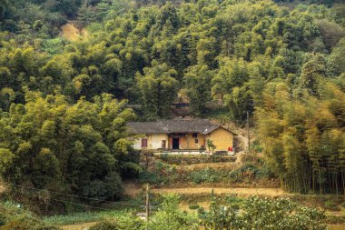 Ufukta mavi gökyüzü olan yüksek yeşil kanyon dağlarında bir kır evi manzarası