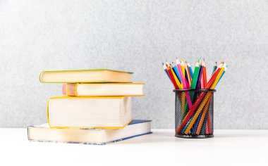 Bir yığın kitap ve beyaz arka planda bir sürü renkli kalem.