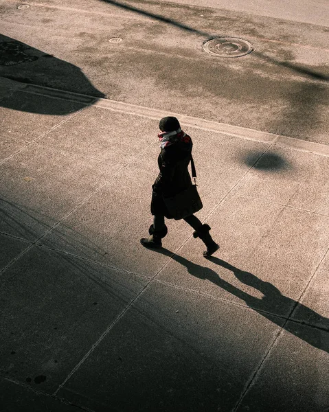 寒い日に暖かい服を着て歩道を歩くスタイリッシュな女性の垂直方向の高い角度のビュー — ストック写真
