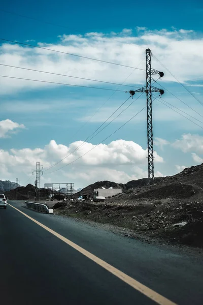 アスファルトの道路 電気ケーブル そして曇り空の下で昼間のサイドロードの山々の美しいショット — ストック写真