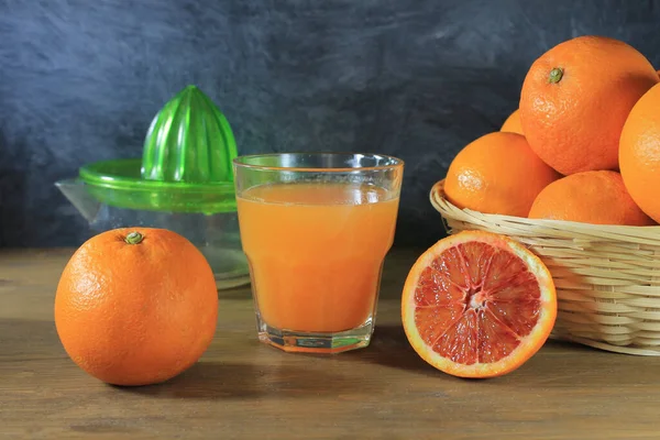 Glas Mit Orangensaft Auf Weißem Tisch Mit Korb Voller Orangen — Stockfoto