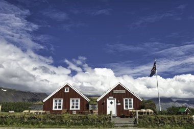 Bulutlu gökyüzünün altındaki iki kırsal evin güzel manzarası.