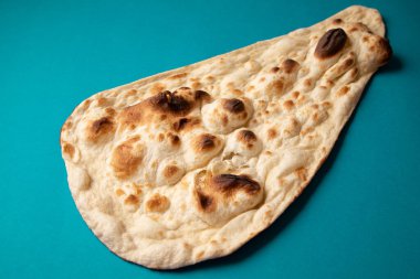 Mavi arka planda bir chapati ekmeğinin yakın plan çekimi.