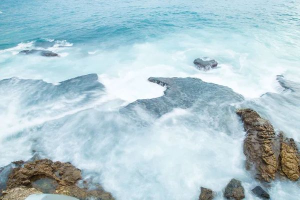 一张美丽的棕色岩石海岸与海浪的照片 — 图库照片